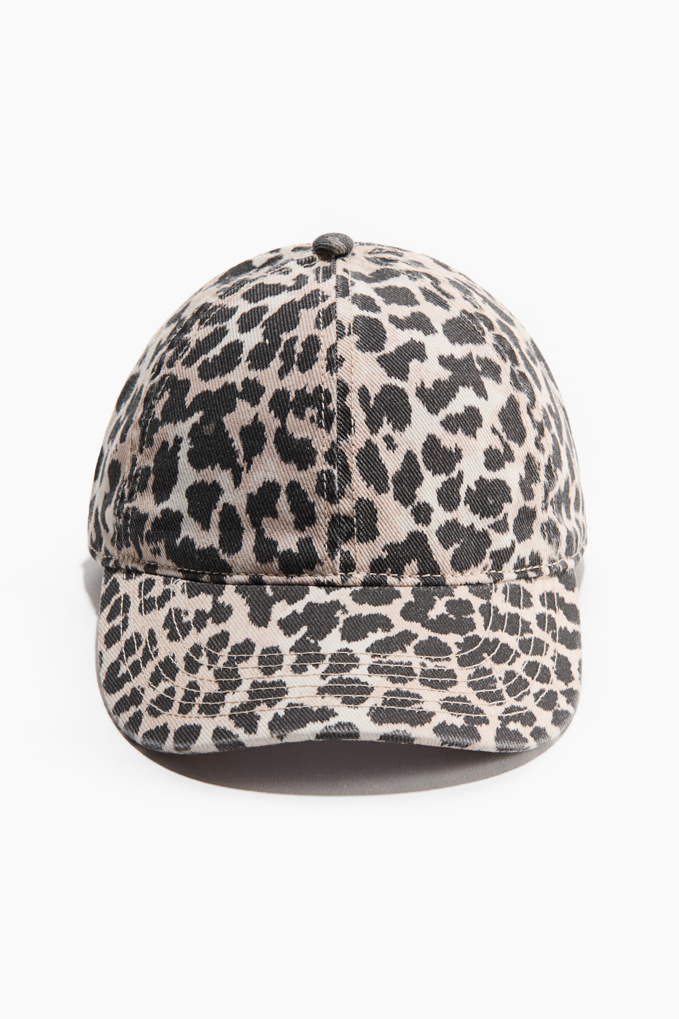 View larger image: A cotton twill cap is facing forward, showcasing a washed leopard print pattern with dark spots on a light background and a structured brim.