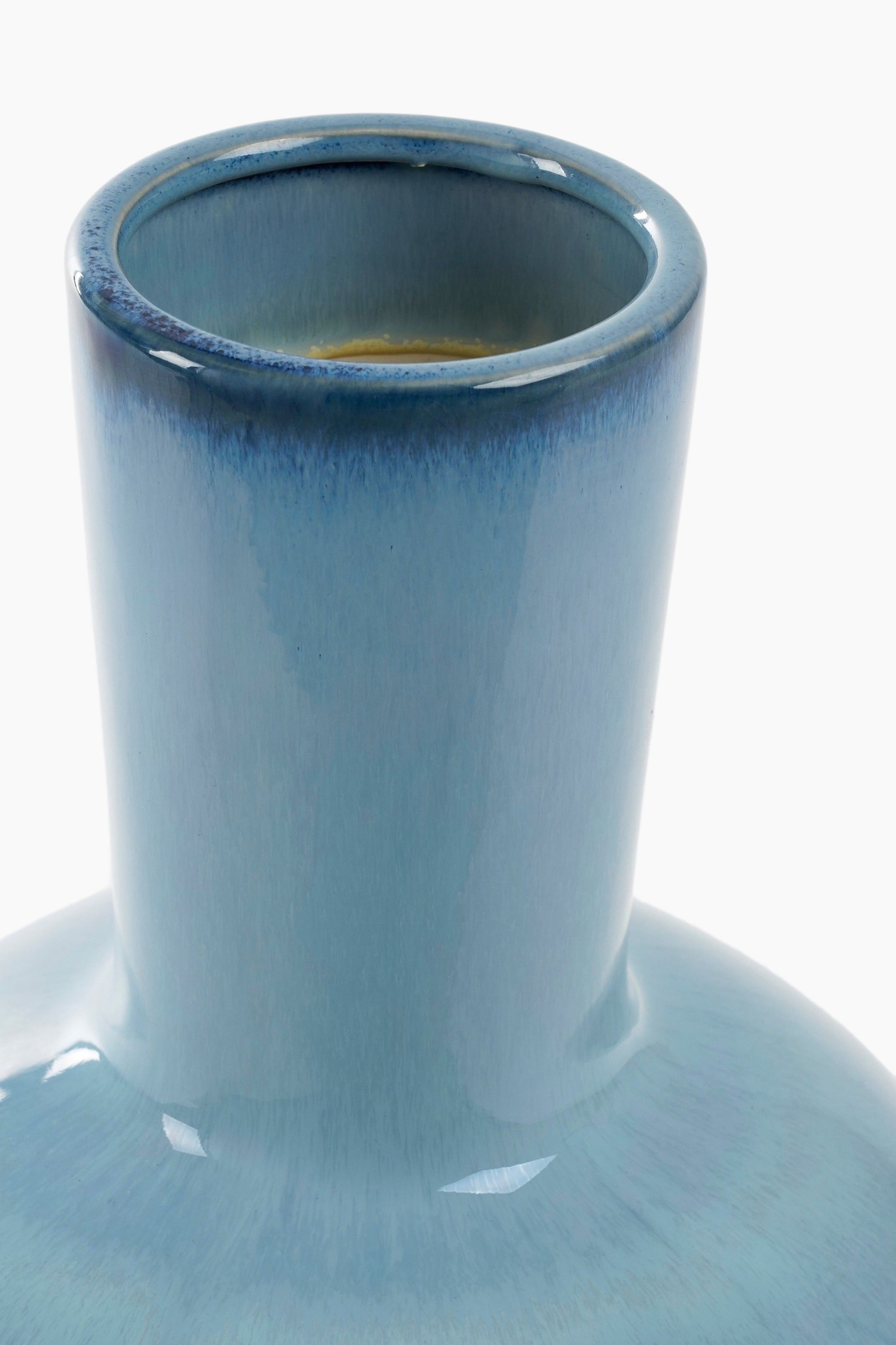 Grotere afbeelding bekijken: Een geglazuurde keramische vaas toont een ombré blauwe kleur, die overgaat van een donkerder blauw aan de rand naar een lichtere blauw op de cilindrische hals en schouders. De opening van de vaas wordt bekeken vanuit een iets verhoogde hoek.