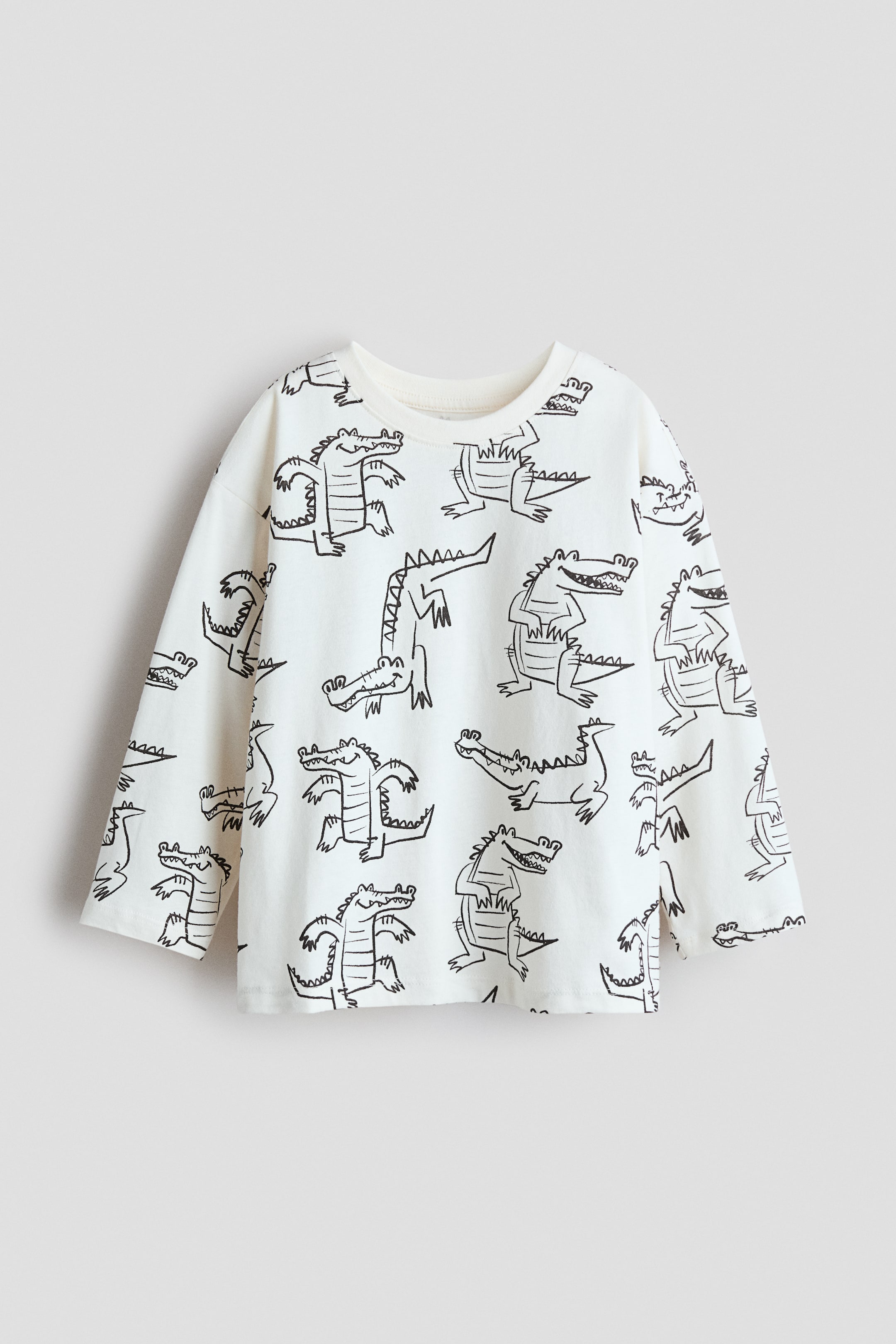 View larger image: A long-sleeve top featuring an all-over pattern of black line-drawn crocodiles on an off-white fabric, presenting a crew neck with a ribbed band and long sleeves. The top showcases a straight hem with small side slits.