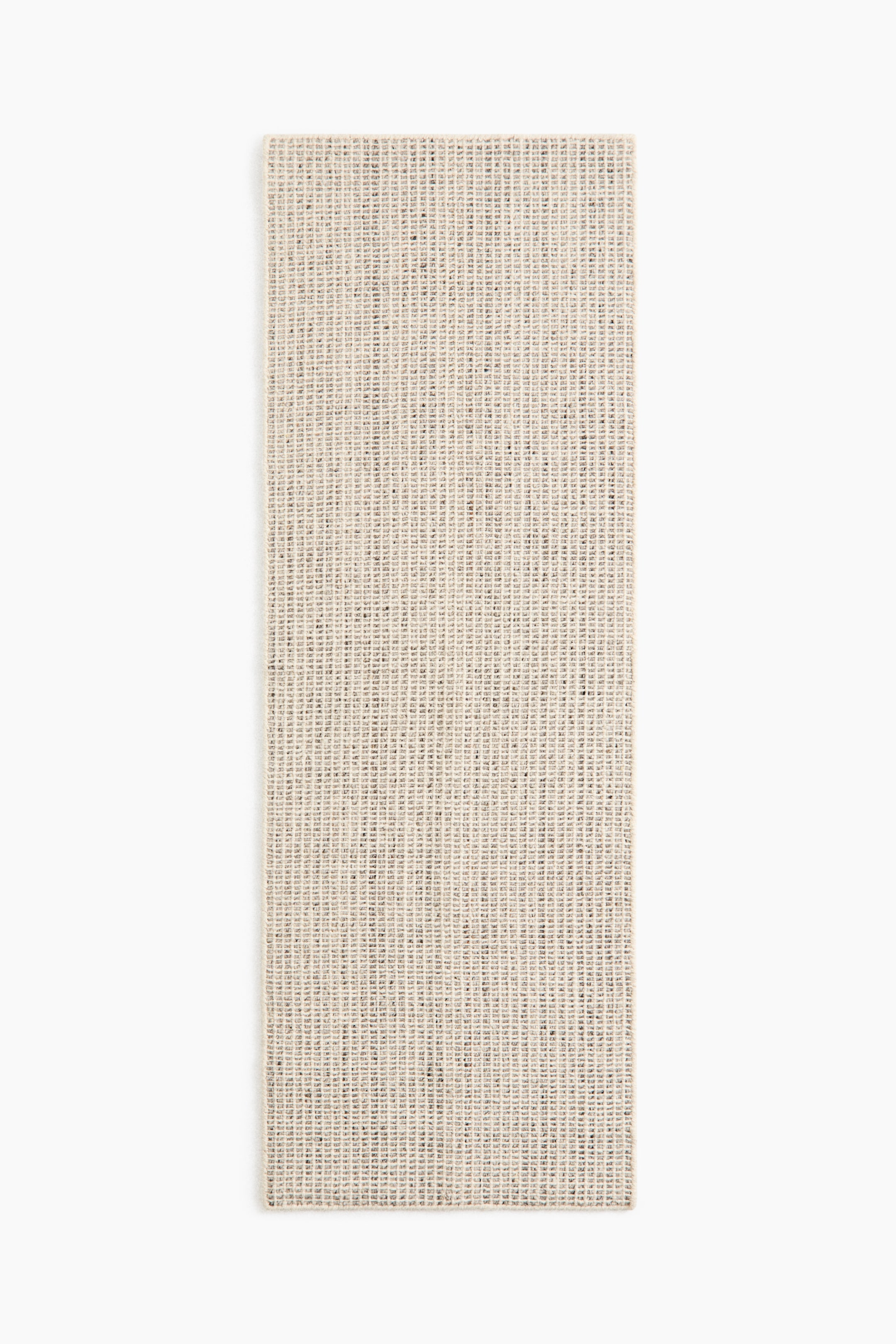 View larger image: A rectangular mat lies flat, featuring a light beige colour with a tight, coarse woven texture and scattered dark flecks.