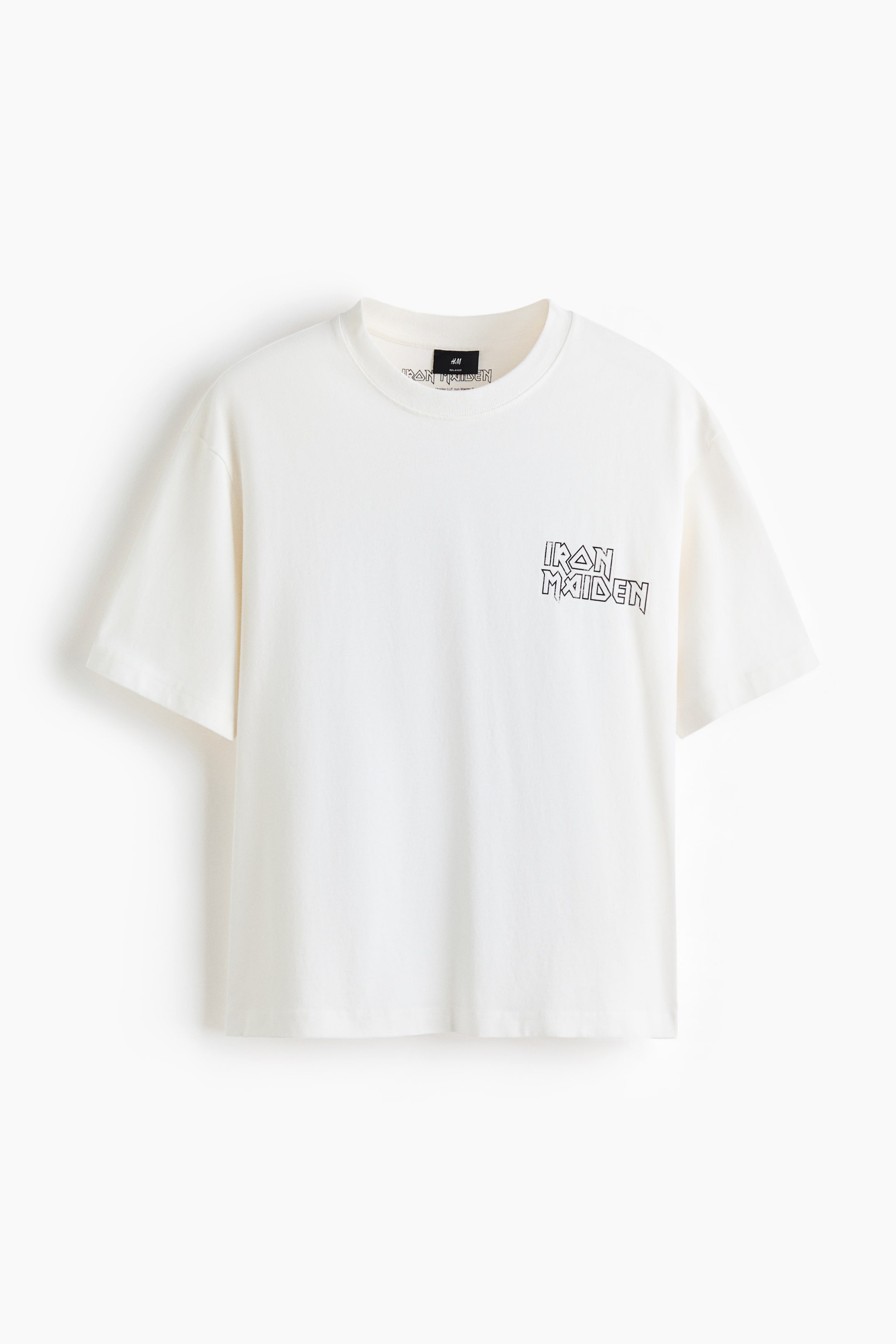 Agrandir l'image: Un t-shirt blanc cassé est présenté à plat, avec un col rond côtelé et des manches courtes et amples. Un logo "IRON MAIDEN" noir est imprimé sur le haut de la poitrine à gauche, et une étiquette noire H&M est visible à l'intérieur du col à l'arrière.