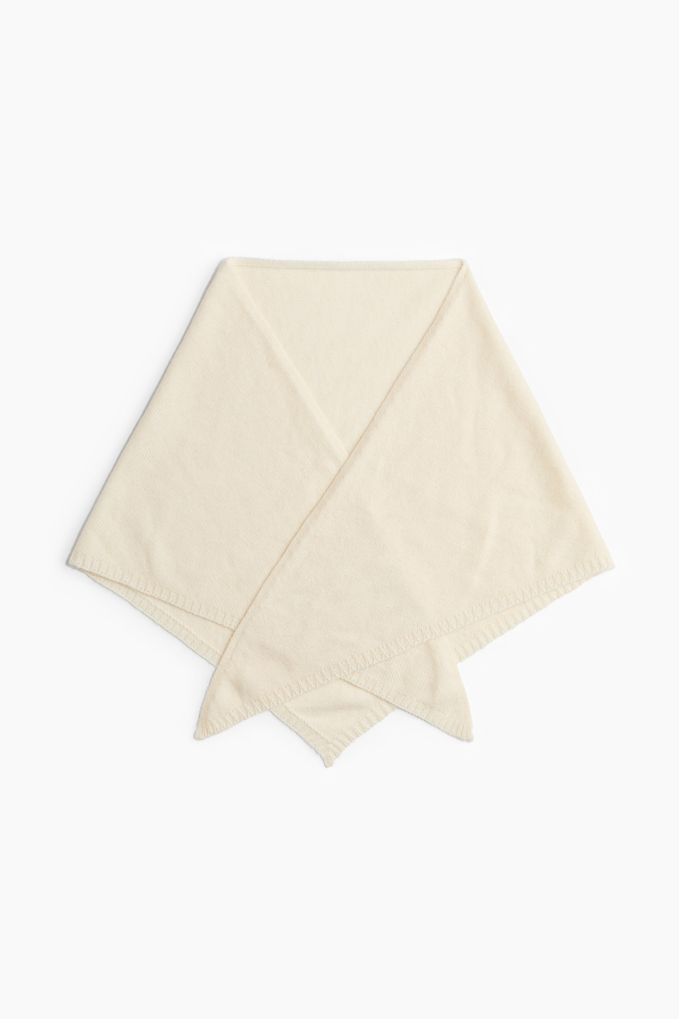 Agrandir l'image: Un foulard triangulaire de couleur crème est posé à plat, mettant en valeur sa texture douce en maille fine et ses bords côtelés. Le foulard est plié à l’avant, avec ses extrémités pointues qui se chevauchent pour en montrer la forme.