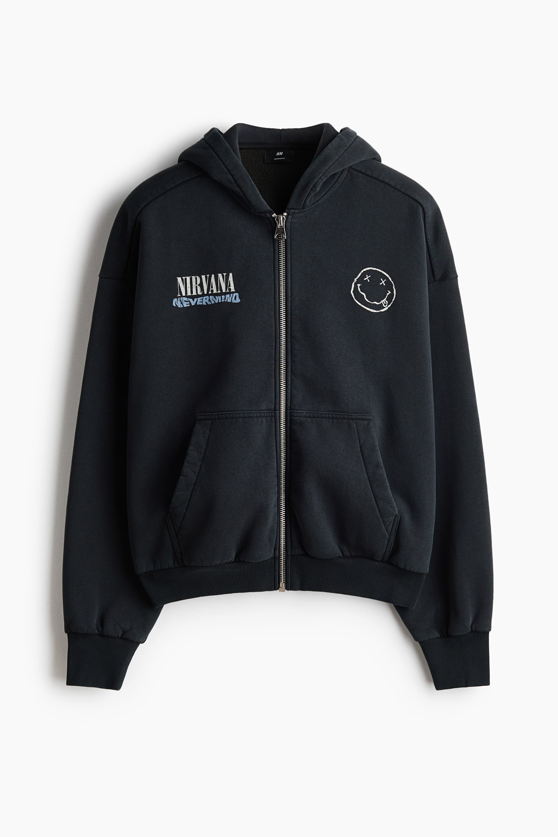 View larger image: A black zip-up hoodie is shown from the front, featuring a full-length zipper and an attached hood. It displays "NIRVANA NEVERMIND" text on the left chest and a white distressed smiley face graphic on the right chest, along with a kangaroo pocket, ribbed cuffs, and a ribbed hem.