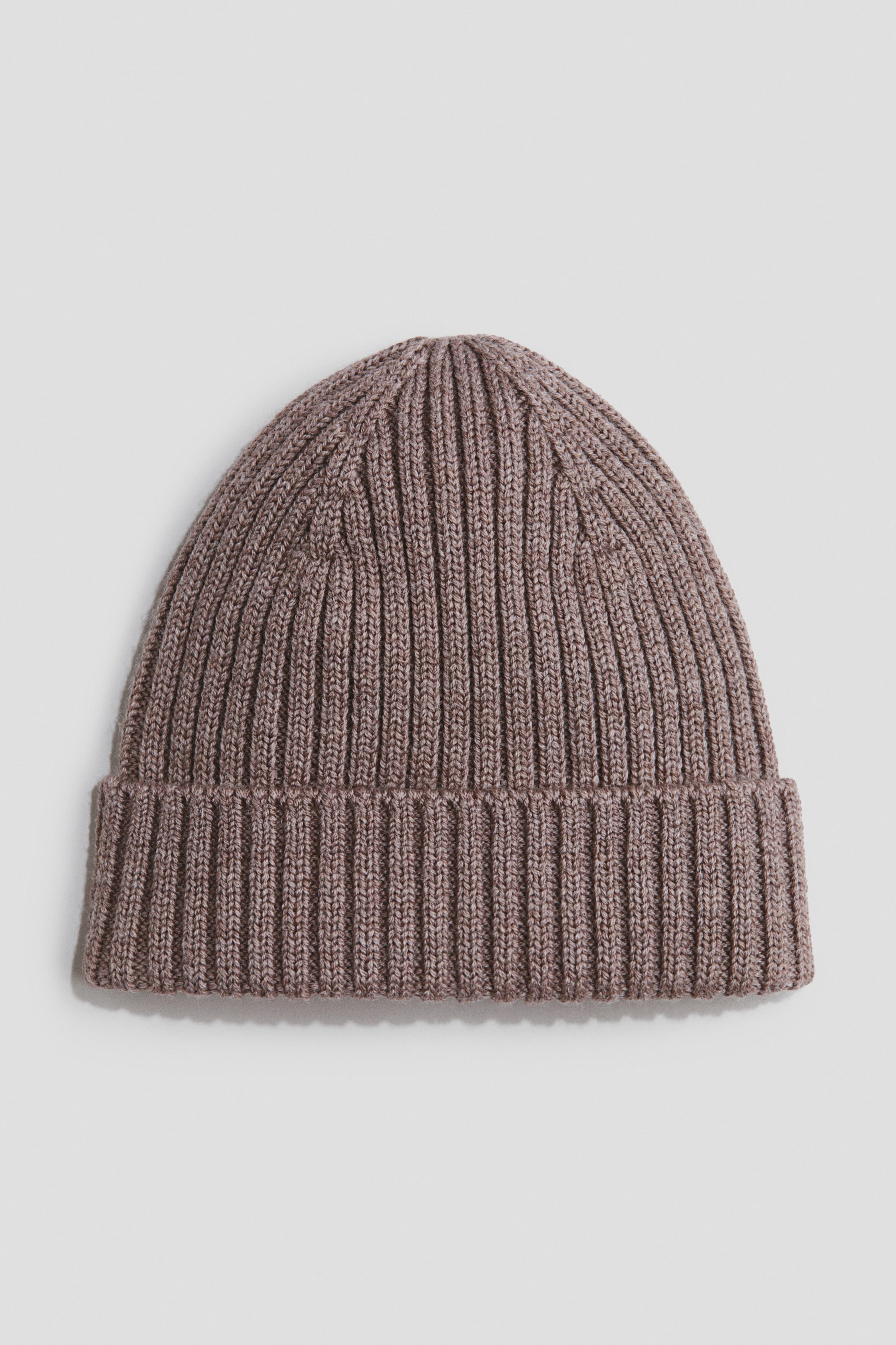 View larger image: A taupe rib-knit beanie is displayed from a slightly elevated front angle, highlighting its unique vertical ribbing and a folded-up hem.