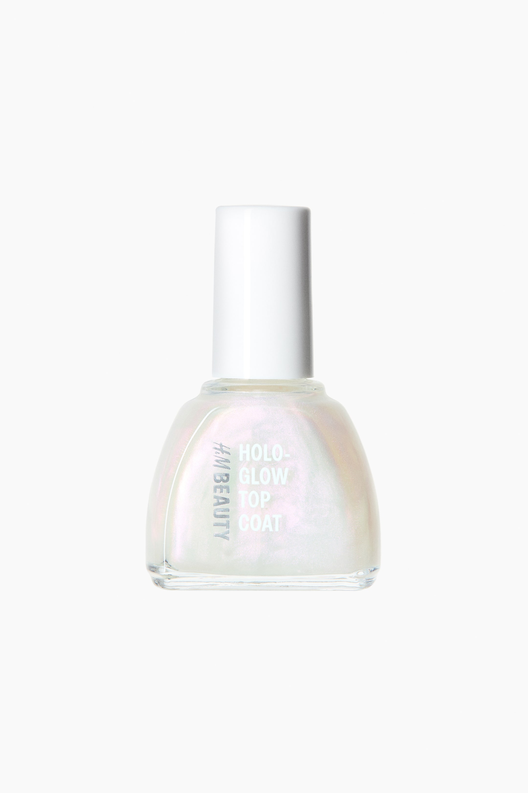 Grösseres Bild ansehen: Eine klare Glasnagellackflasche steht im Vordergrund und enthält eine perlmuttartige, irisierende Flüssigkeit. Die Flasche hat einen weißen zylindrischen Verschluss und ist mit "H&M BEAUTY HOLO-GLOW TOP COAT" in silberner Schrift beschriftet.