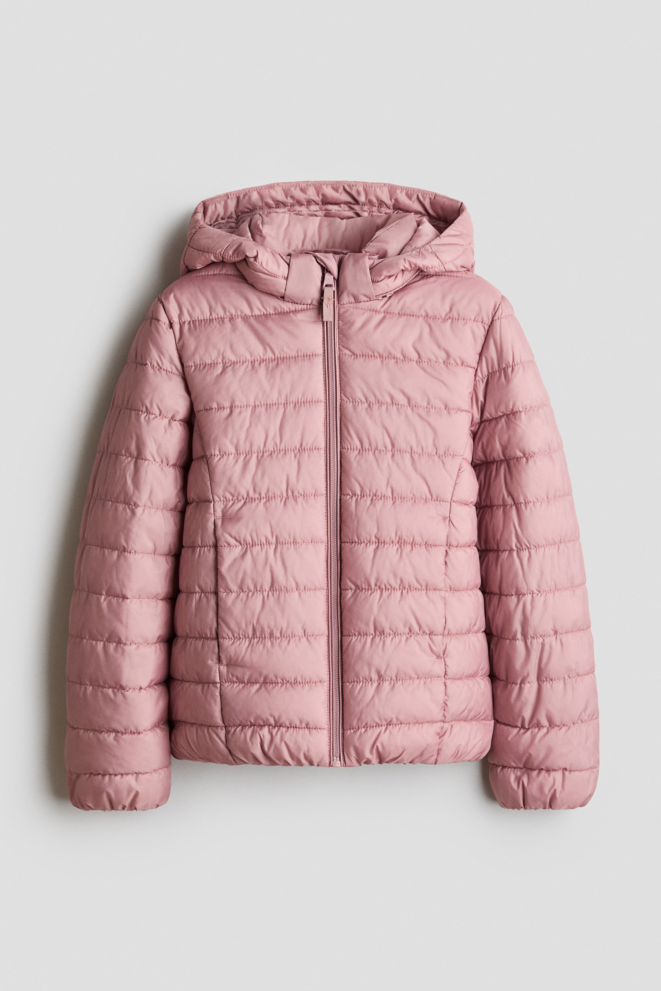 Ampliar la imagen: Se muestra una chaqueta acolchada rosa de frente, con capucha desmontable, cuello alto y cierre completo con cierre al frente en el centro. Presenta acolchado horizontal, bolsillos laterales discretos y ribetes estrechos elásticos en la capucha, los puños y el dobladillo.