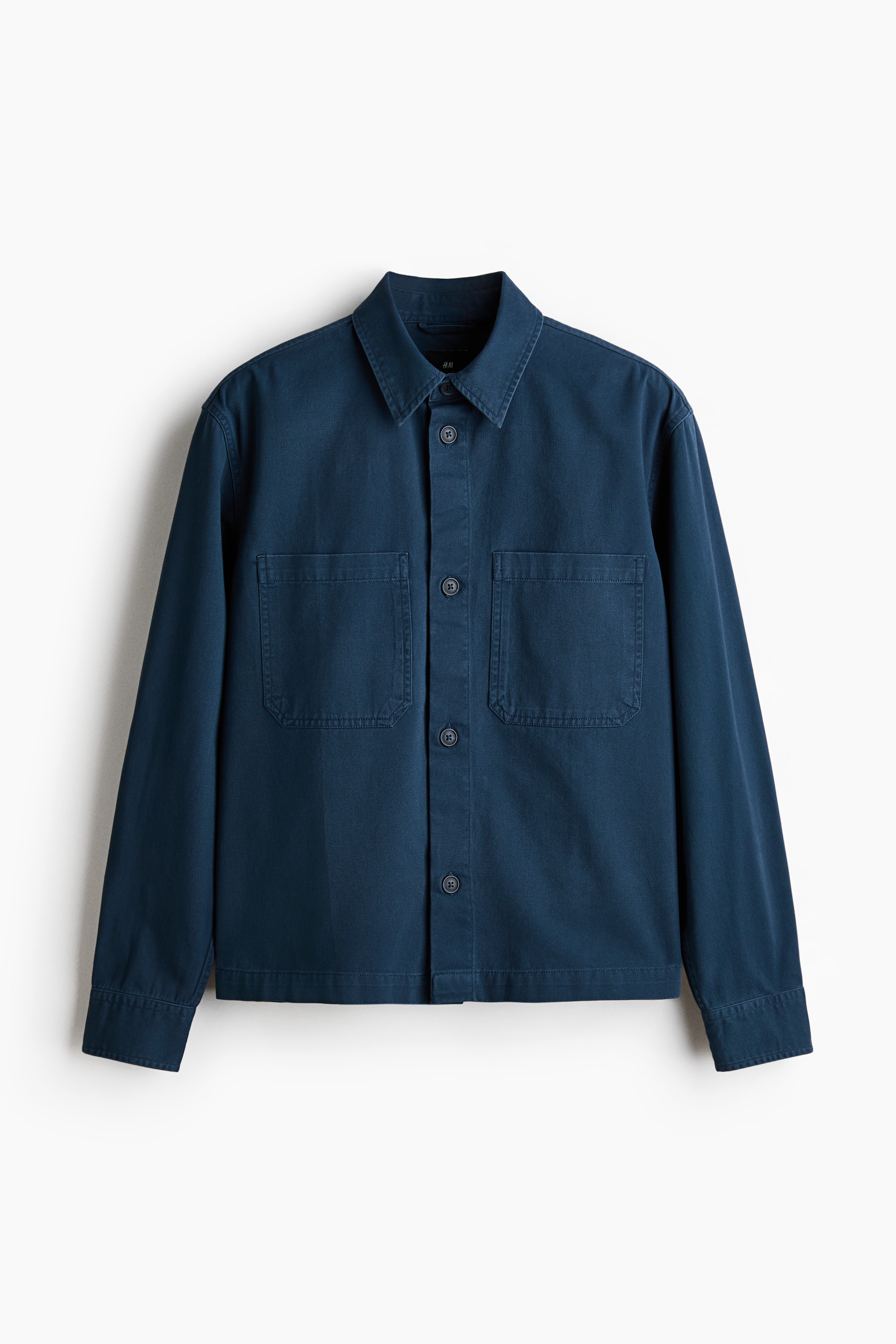 View larger image: A dark blue shirt is shown from the front, featuring a pointed collar and a button-front closure with dark round buttons. It has two large patch pockets on the chest, and long sleeves finished with buttoned cuffs.