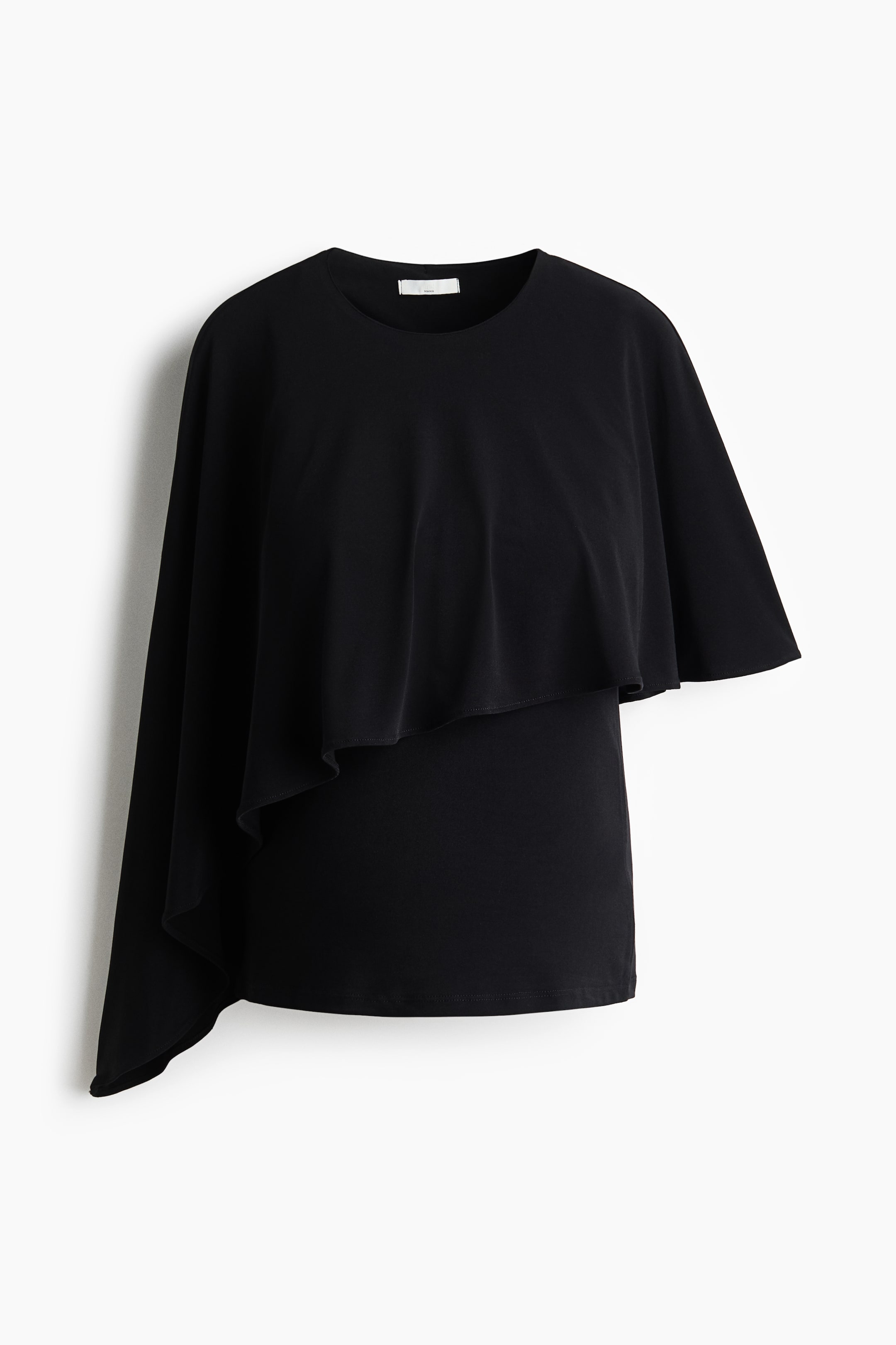 View larger image: A black top is shown from the FRONT, featuring a round neckline and an asymmetrical cape-like overlay. The overlay extends from the left shoulder, draping down the left side, while the right side of the overlay finishes shorter.