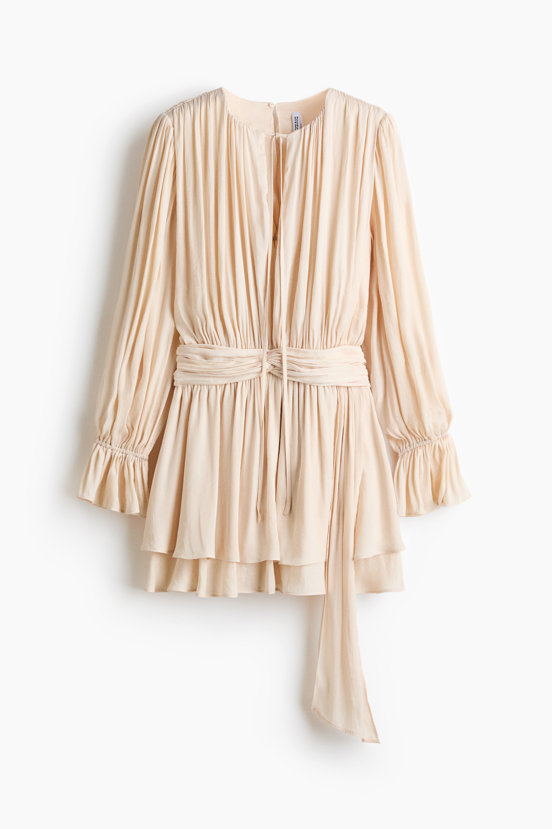 Größeres Bild ansehen: Das kurze, locker sitzende Kleid präsentiert ein drapiertes Gewebe und verfügt über einen runden Ausschnitt mit einem kleinen Schlitz und schmalen Bändern an der Vorderseite. Lange Ärmel zeigen eine schmale Elastizierung oberhalb der gerüschten Manschetten, und ein drapierter Taillenbund bildet ein Knotendetail mit einem langen Ende, während der Rockteil in Lagen erscheint.