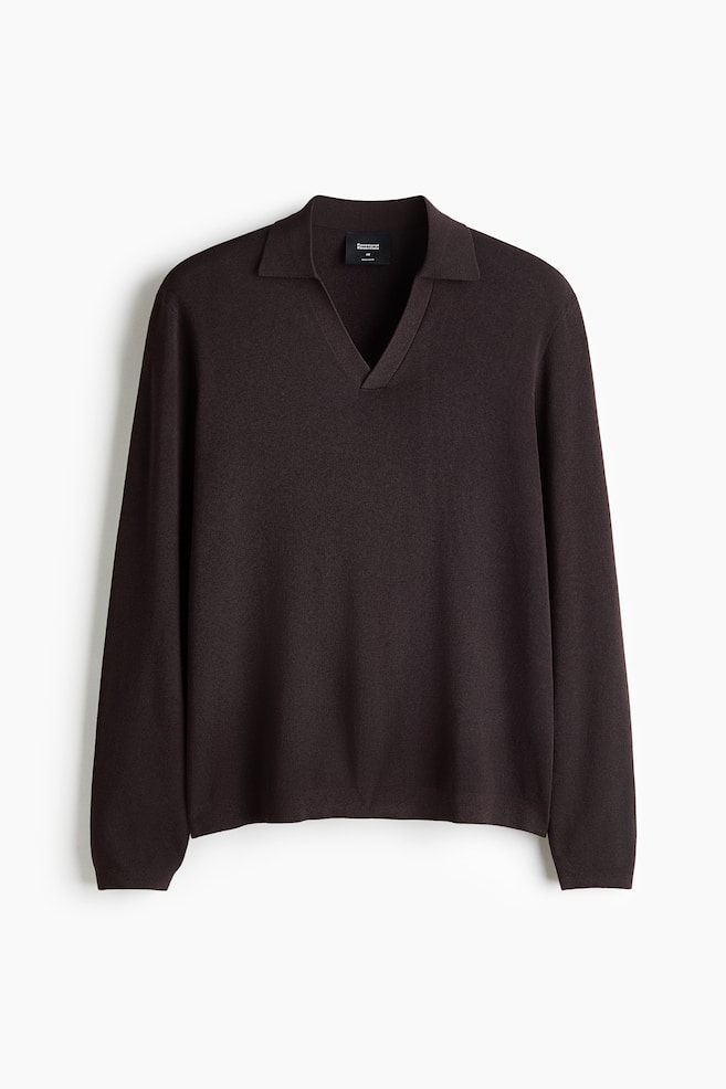 Se muestra un suÃ©ter tipo polo de punto fino en color cafÃ© oscuro, visto de frente, con un corte relajado, hombros caÃ­dos y mangas largas con puÃ±os acanalados. El diseÃ±o incluye un cuello clÃ¡sico con abertura en forma de V sin botones y un dobladillo recto. - 1