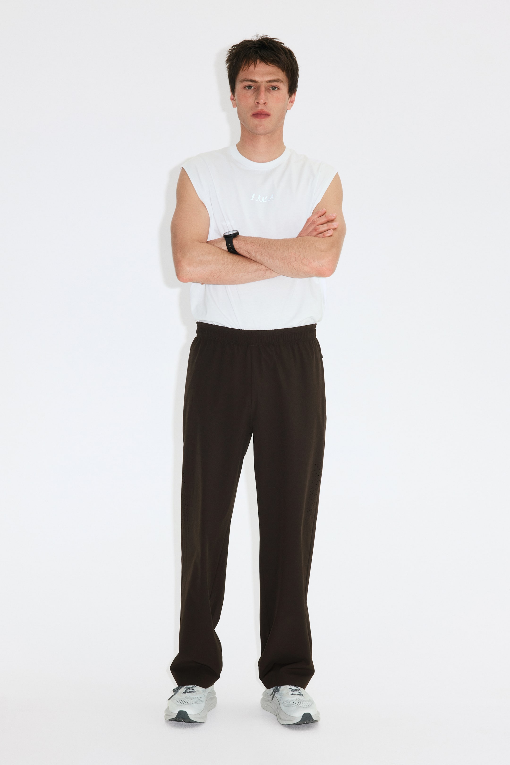 Agrandir l'image: Pantalon brun foncé doté d'une taille élastiquée et d'une coupe droite, avec de subtiles perforations le long des côtés des jambes. Le pantalon est présenté de face.