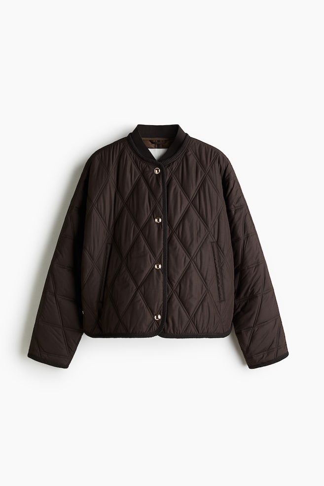 A dark brown quilted jacket is presented from the FRONT, featuring diamond-shaped quilting throughout. It is designed with a ribbed bomber collar, a front placket secured by gold-toned snap buttons, and two slit pockets. The jacket is detailed with black piping along the placket, collar, ribbed cuffs, and ribbed hem. - 1
