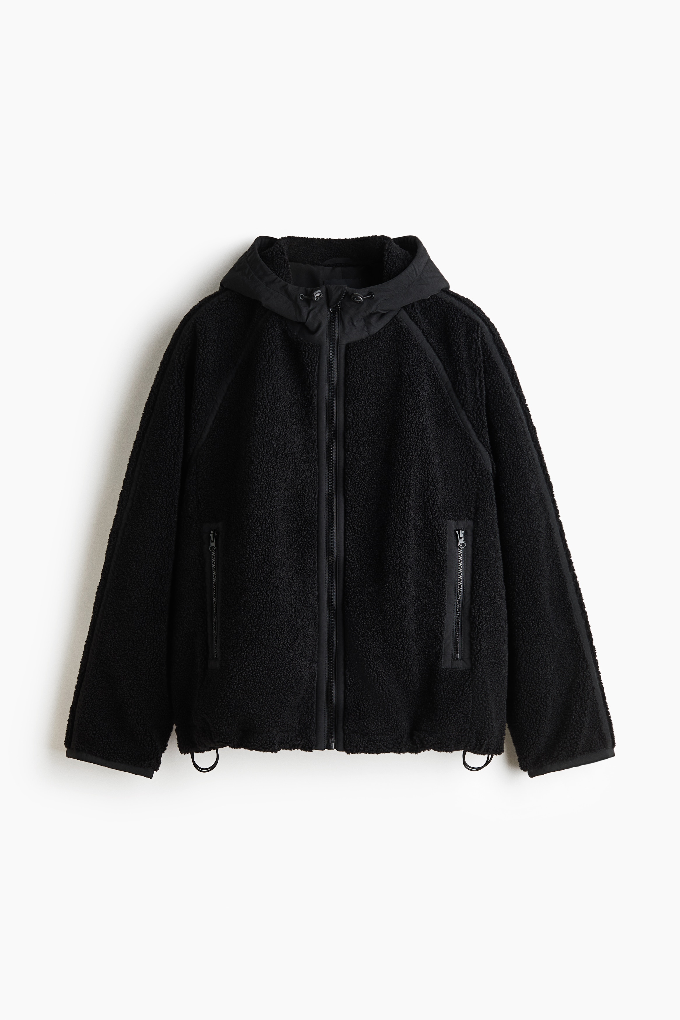 Une veste en teddy fleece marron est portÃ©e ouverte par le mannequin, superposÃ©e sur un polo gris clair et un jean gris foncÃ©. La veste prÃ©sente une finition douce et texturÃ©e, une capuche et de longues manches raglan.