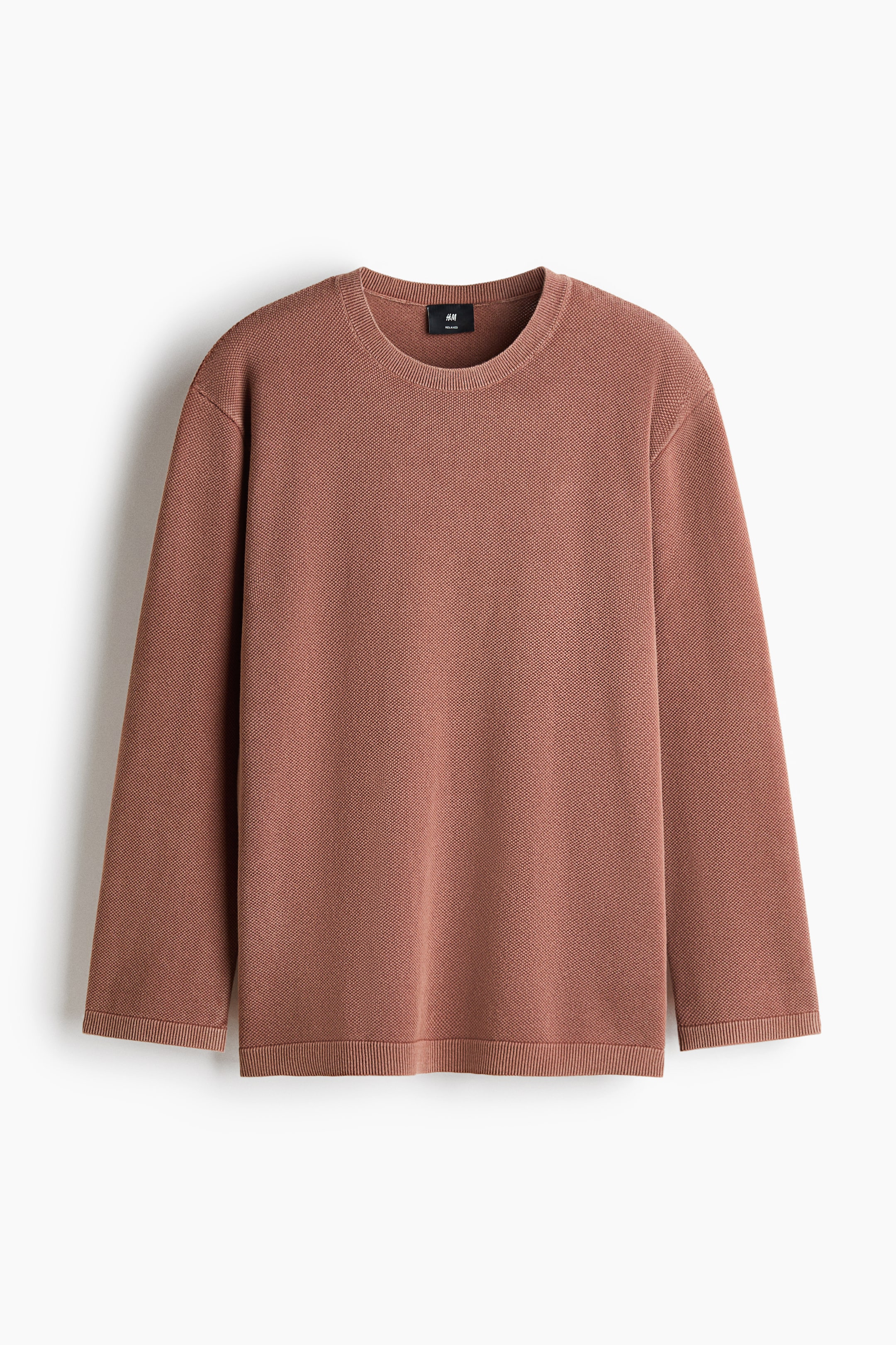 View larger image: A textured cotton knit sweater in a dusty rose colour is shown from the front, featuring a relaxed silhouette with a round neckline and long sleeves. Ribbing trims the collar, cuffs, and straight hem.