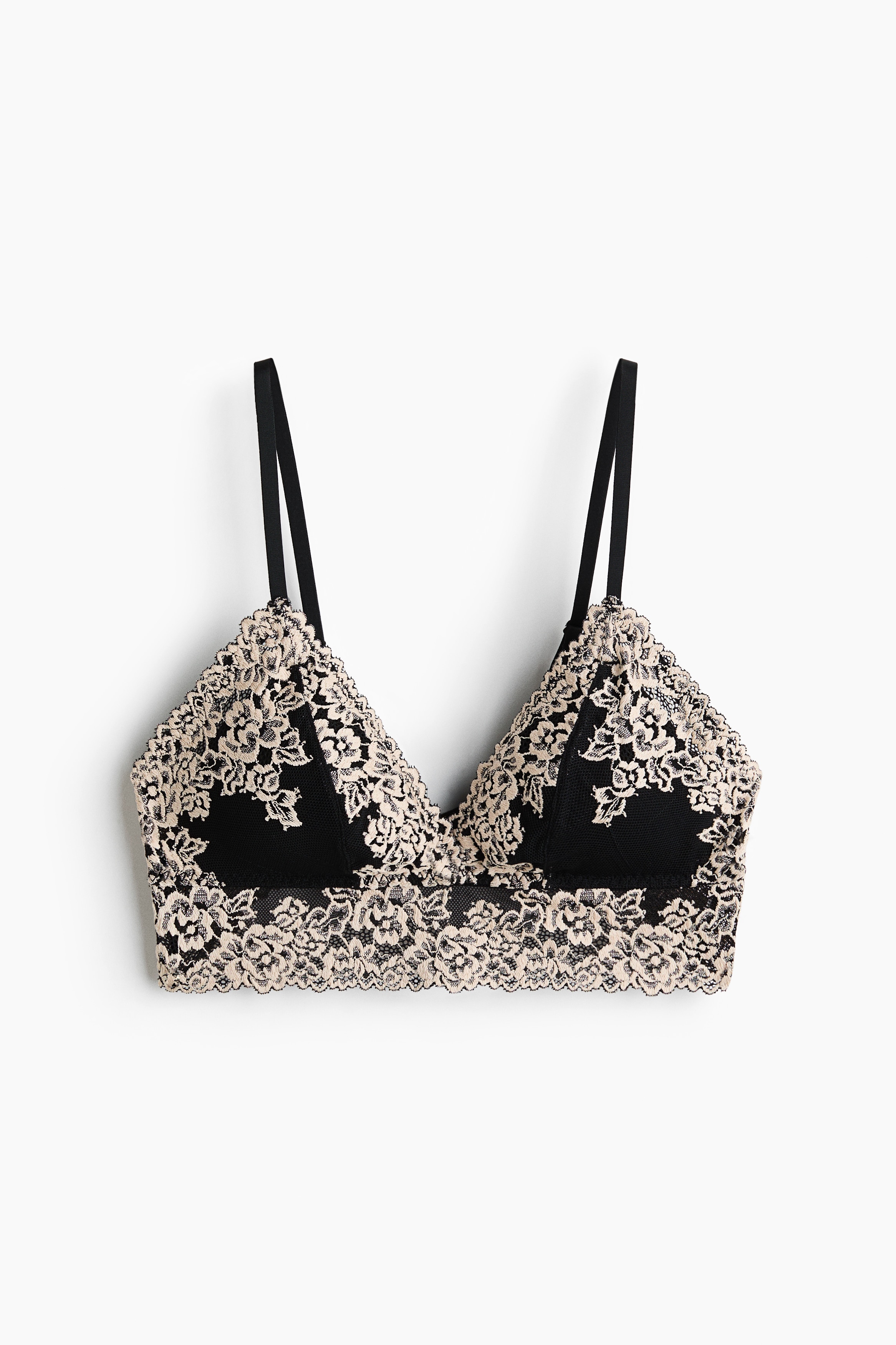 A black triangle bra showcasing cream floral lace detailing over the black fabric of the cups. Designed with thin black shoulder straps and a soft-cup construction.