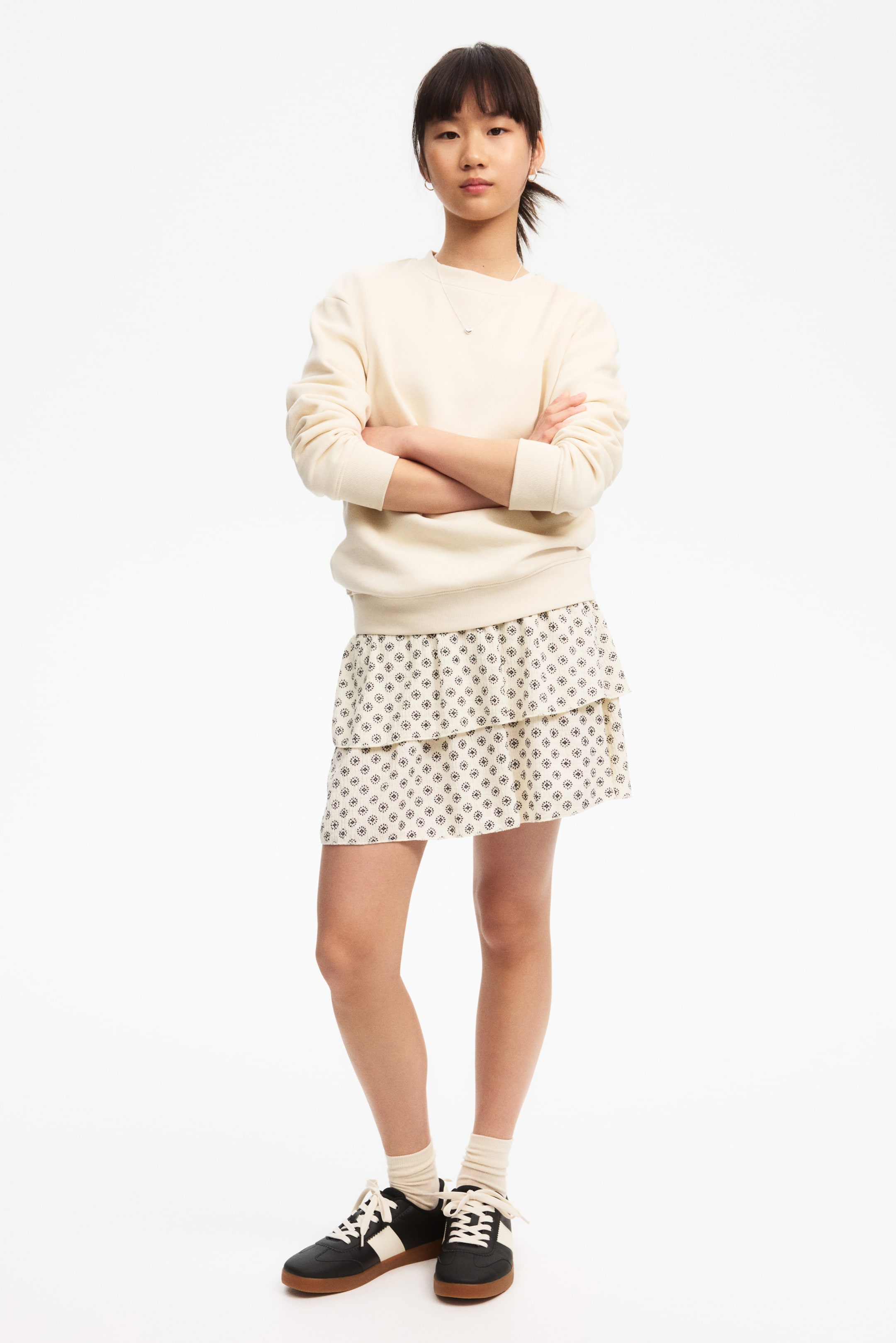 Agrandir l'image: Un sweat-shirt crème est présenté en vue de face, avec un col rond, des manches longues, une coupe décontractée, des poignets côtelés et un ourlet côtelé.