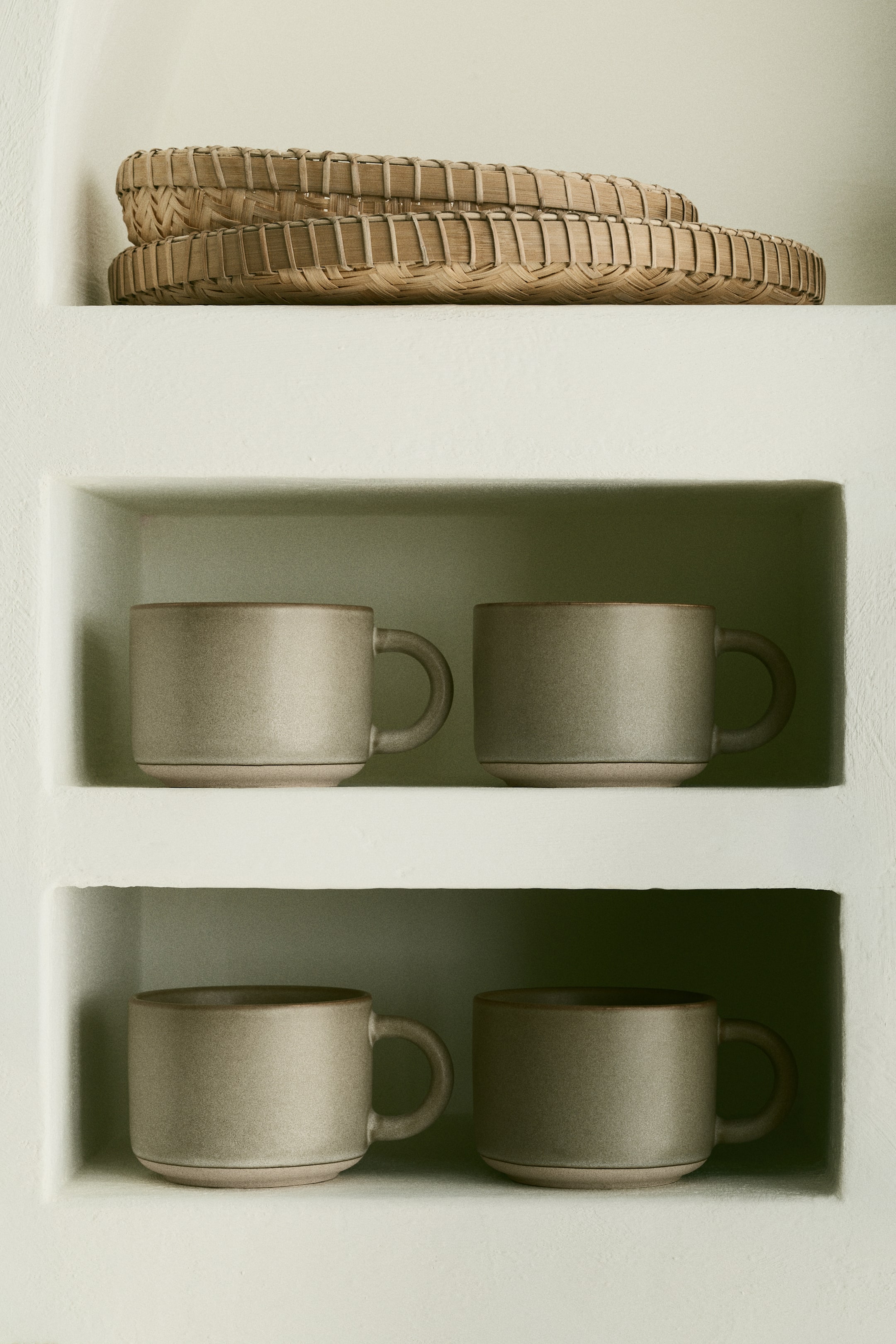 Voir une image plus grande: Les tasses en grès présentent un émail réactif, créant une coloration variée et conférant à chaque pièce une apparence unique. La base de chaque tasse reste non émaillée, révélant une couleur contrastante et une finition naturellement texturée. Chaque tasse arbore une forme cylindrique avec une poignée et est orientée vers l'avant.