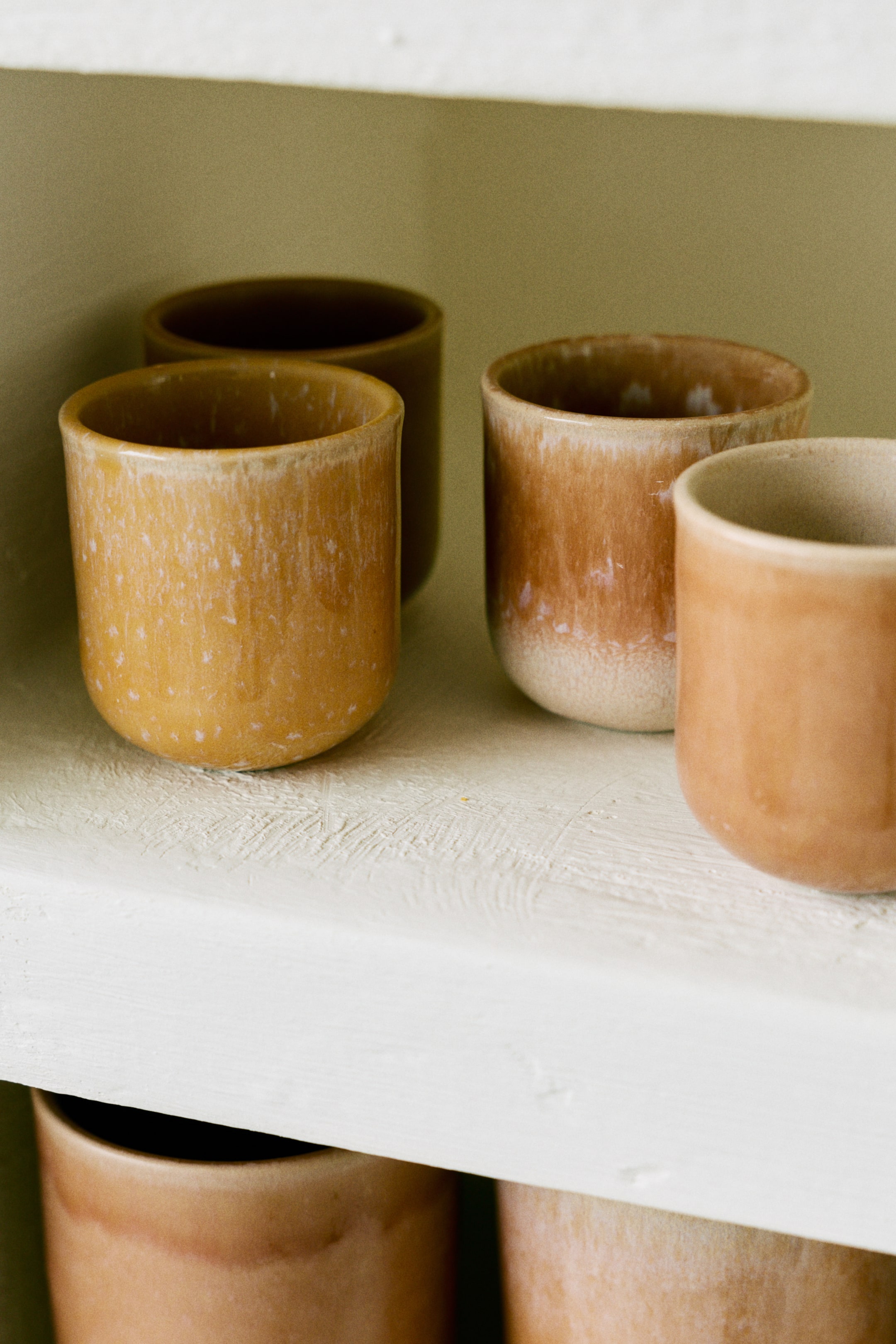 Agrandir l'image: Un ensemble de tasses à espresso en grès émaillé présente une forme classique et un aspect artisanal. Chaque tasse arbore une coloration unique et variée grâce à un émail réactif, affichant des nuances de marron, d'orange et de beige.