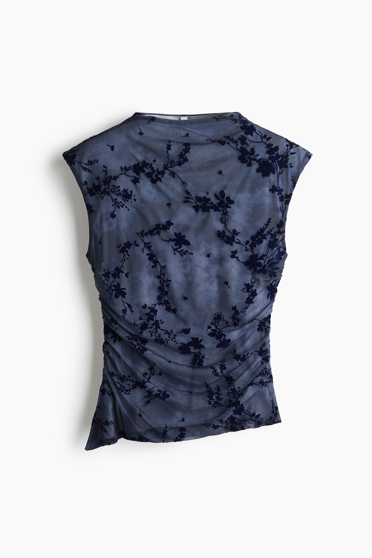 A sleeveless, fitted sheer mesh top is shown from the front, featuring an all-over dark floral flock print over a solid lining. The design features a high neck, gathered side seams that create draped ruching across the body, and an asymmetrical hem.