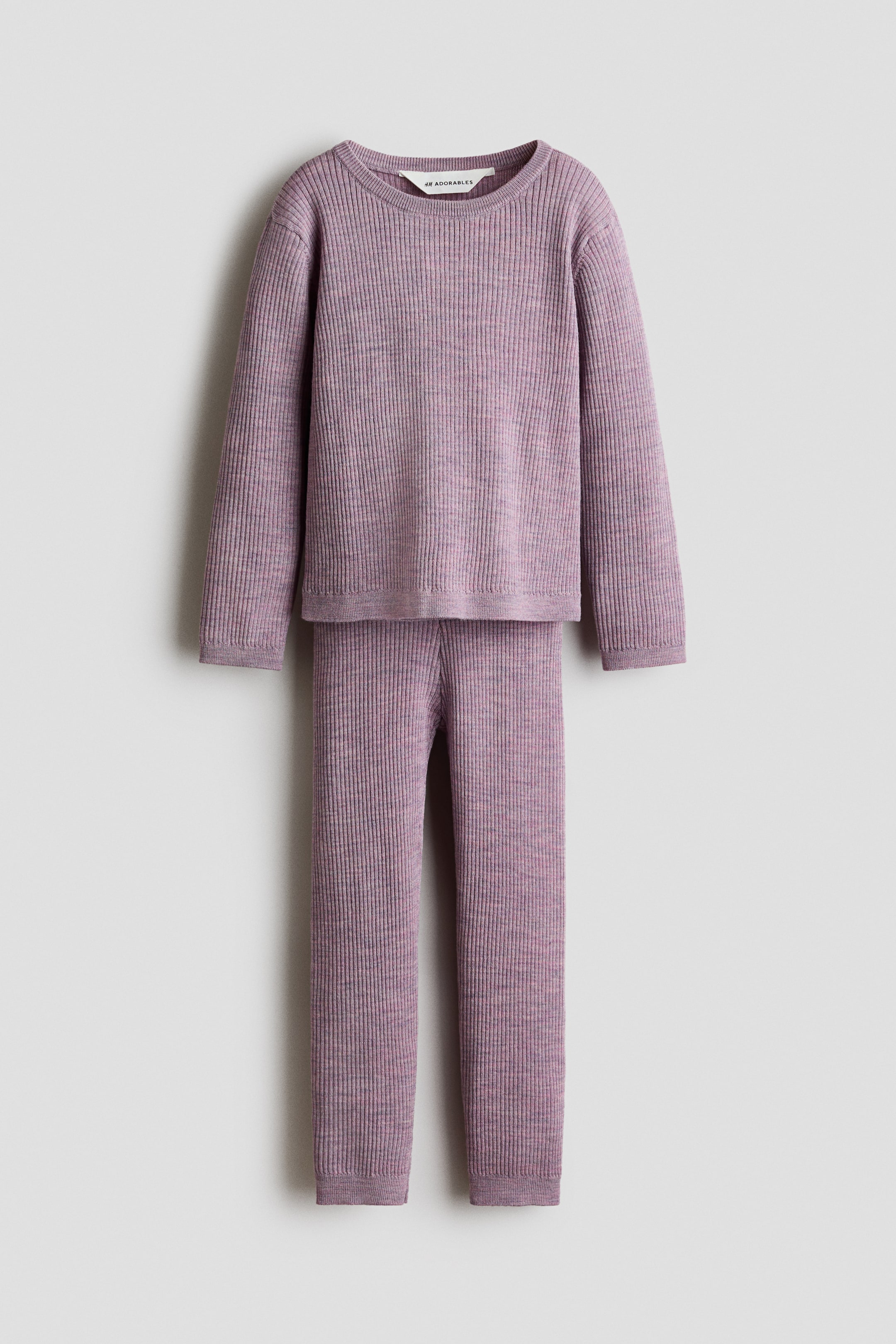 View larger image: The H&M Adorables merino wool set showcases a heathered light purple rib-knit jumper paired with matching leggings, arranged flat and front-facing. The jumper boasts long sleeves, fine-knit ribbing at the round neckline, cuffs, and hem, with the "H&M Adorables" label prominently displayed at the back of the neckline. Meanwhile, the leggings feature fine-knit ribbing at their hems.