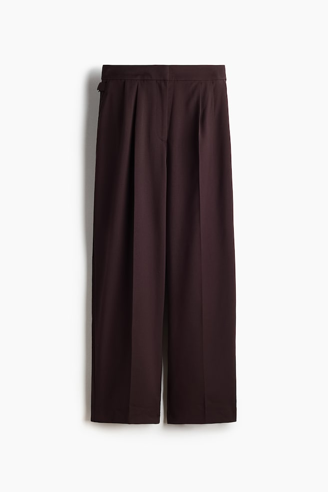 The deep plum wide-leg trousers are hanging flat, featuring prominent front pleats, a flat waistband, and a visible side adjuster on the left hip. - 1