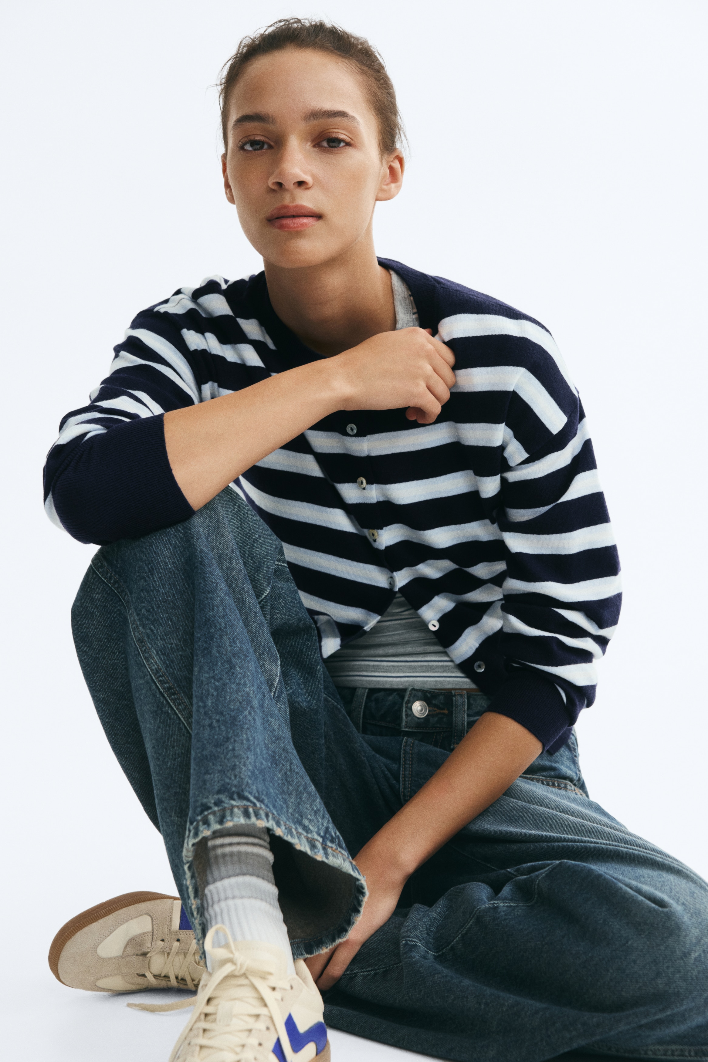 Má»t Ã¡o cardigan dá»t kim káº» sá»c ÄÆ°á»£c chá»¥p chÃ­nh diá»n, hiá»n thá» cÃ¡c sá»c ngang mÃ u xanh navy, tráº¯ng vÃ  xanh nháº¡t. Thiáº¿t káº¿ cÃ³ cá» trÃ²n, hÃ ng cÃºc phÃ­a trÆ°á»c vá»i cÃ¡c nÃºt mÃ u sÃ¡ng, vai xuÃ´i, tay dÃ i káº¿t thÃºc báº±ng bo tay gÃ¢n mÃ u navy trÆ¡n kÃ©o dÃ i, Äá»ng bá» vá»i pháº§n bo gáº¥u Ã¡o gÃ¢n rá»ng.