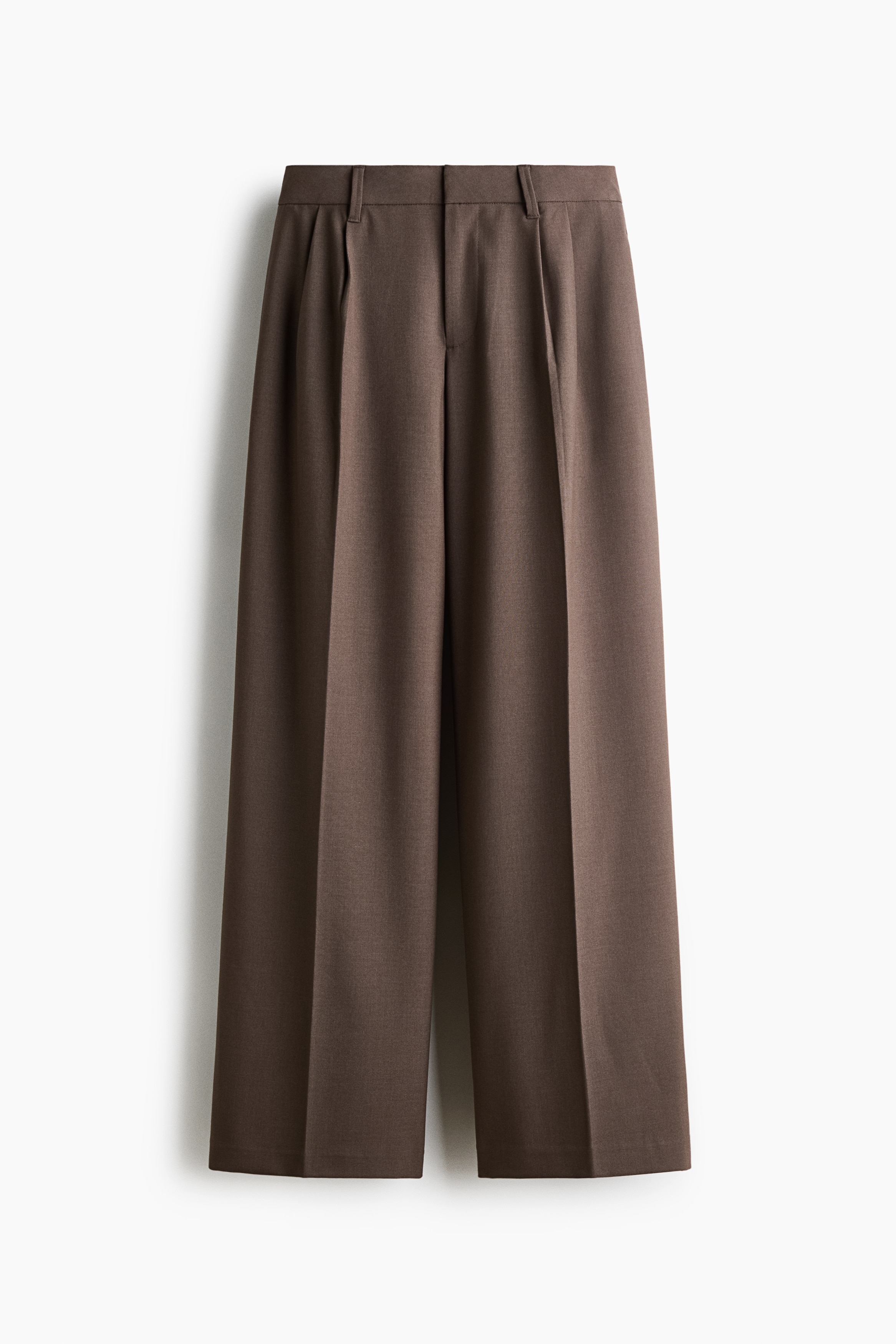 Tailored wide-leg trousers in a dark taupe woven fabric are worn by the model, featuring a low waist and front creases. A plaid shirt is tied around the waist of the trousers, which are paired with a cream long-sleeve crop top.