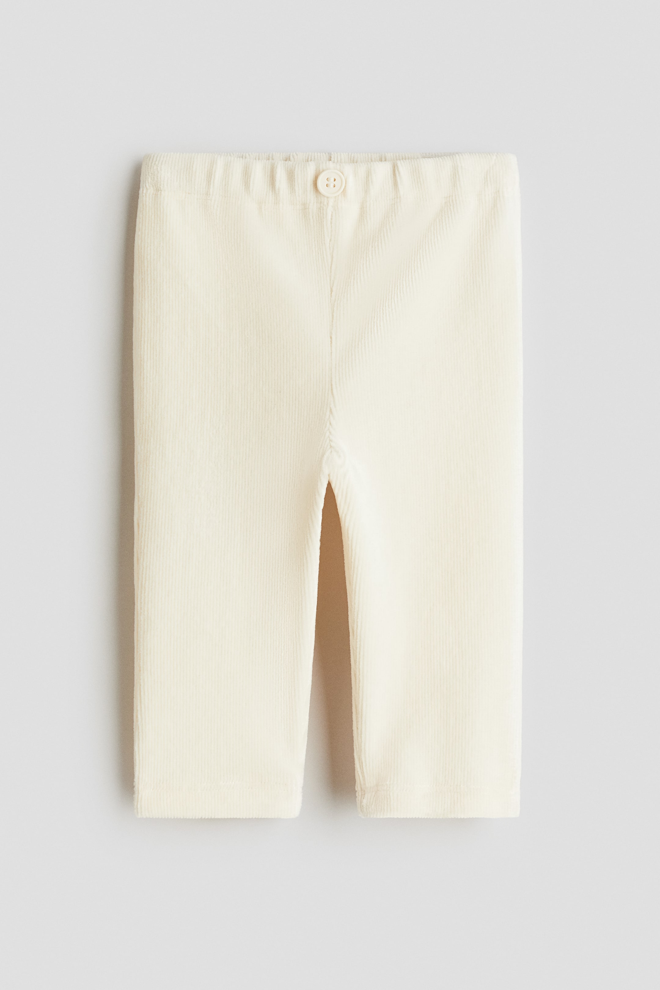 View larger image: A pair of off-white corduroy pants is shown from the front, featuring a gathered waistband with a single decorative button at the center, and straight legs with simple hems.