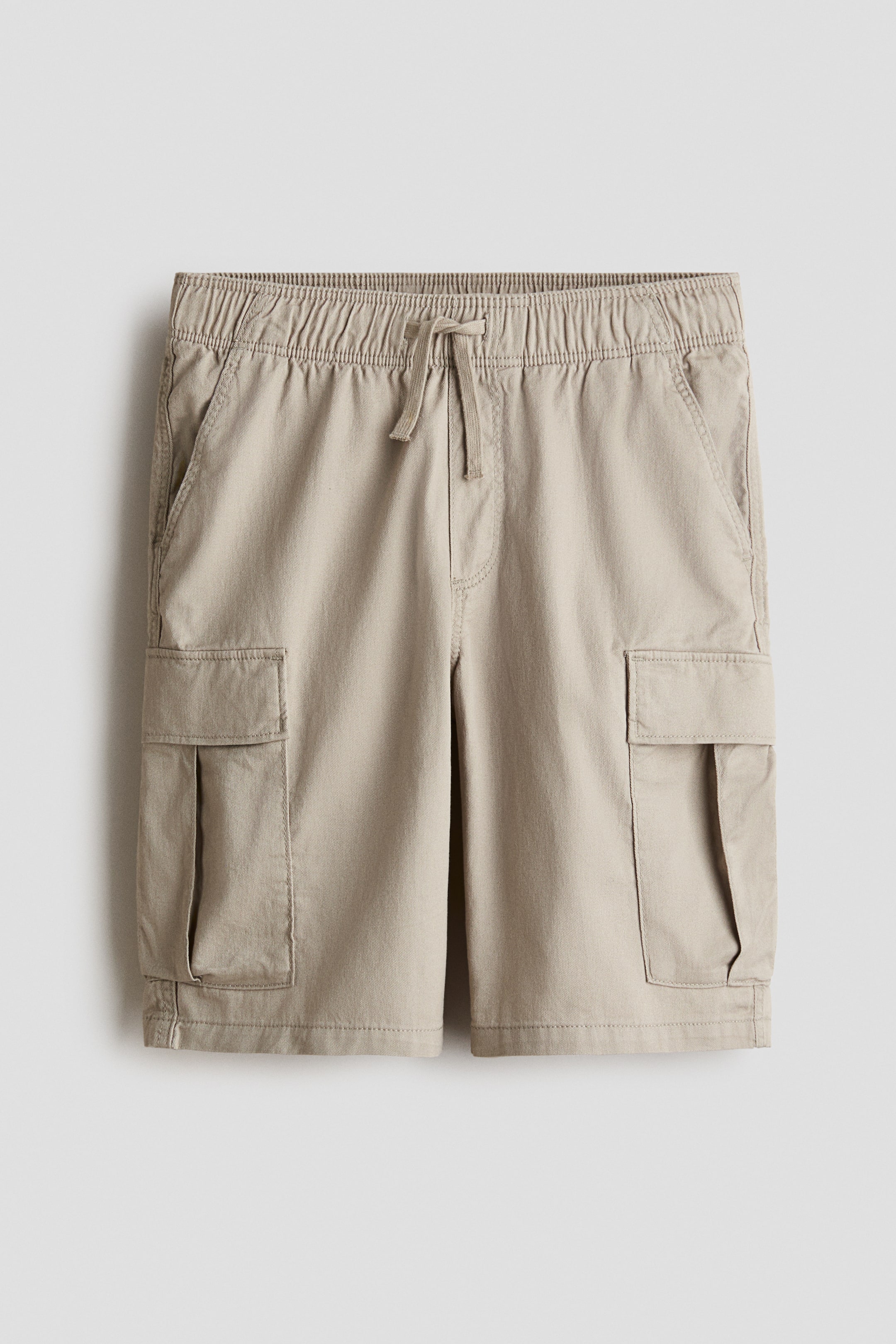 View larger image: Knee-length shorts in soft cotton twill are on display from the front, featuring an elasticated drawstring waist, a mock fly, diagonal side pockets, and flap leg pockets.