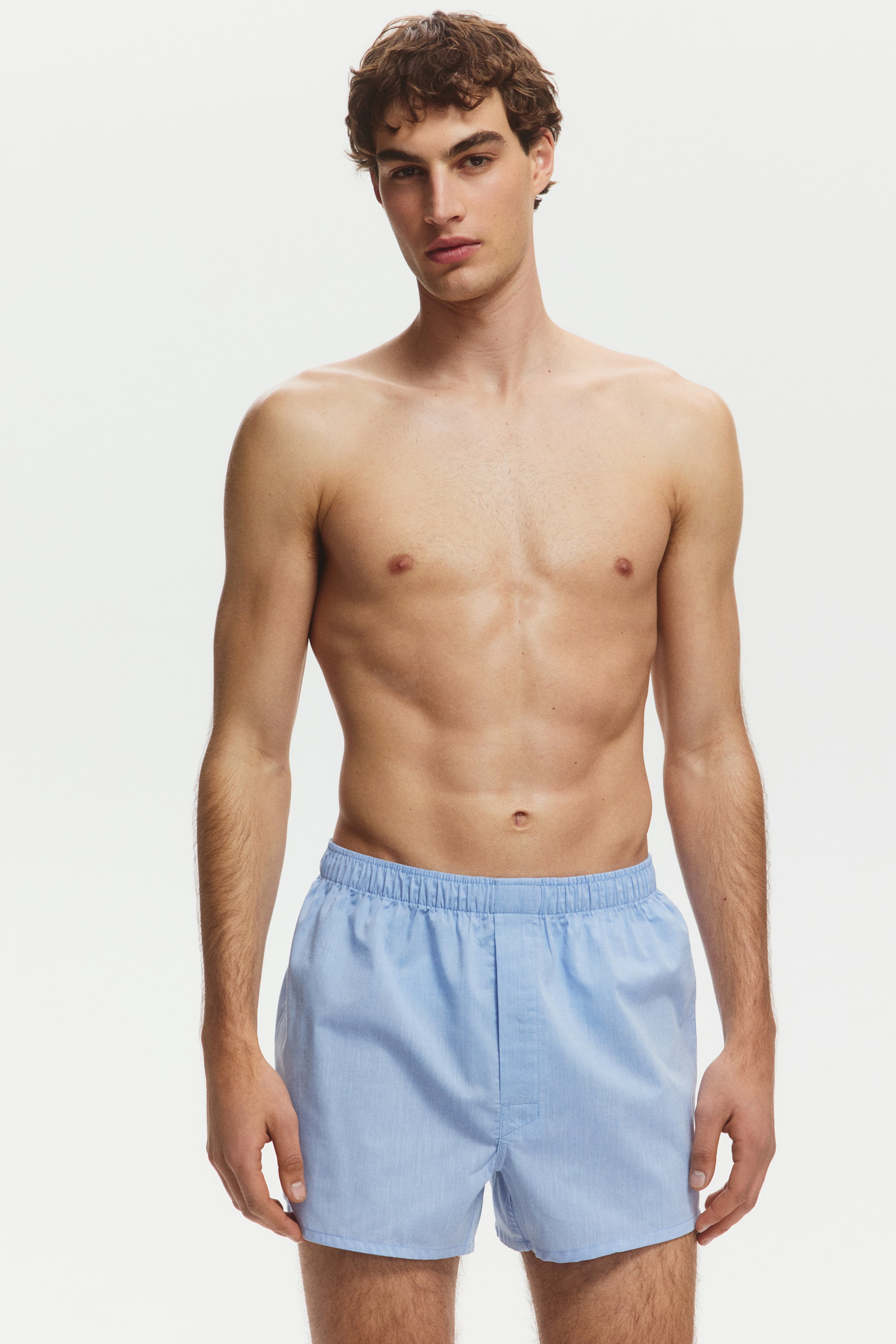 View larger image: Light blue boxers are being worn, featuring an elasticated waistband and a central fly. They offer a relaxed fit in a subtly textured light blue fabric.