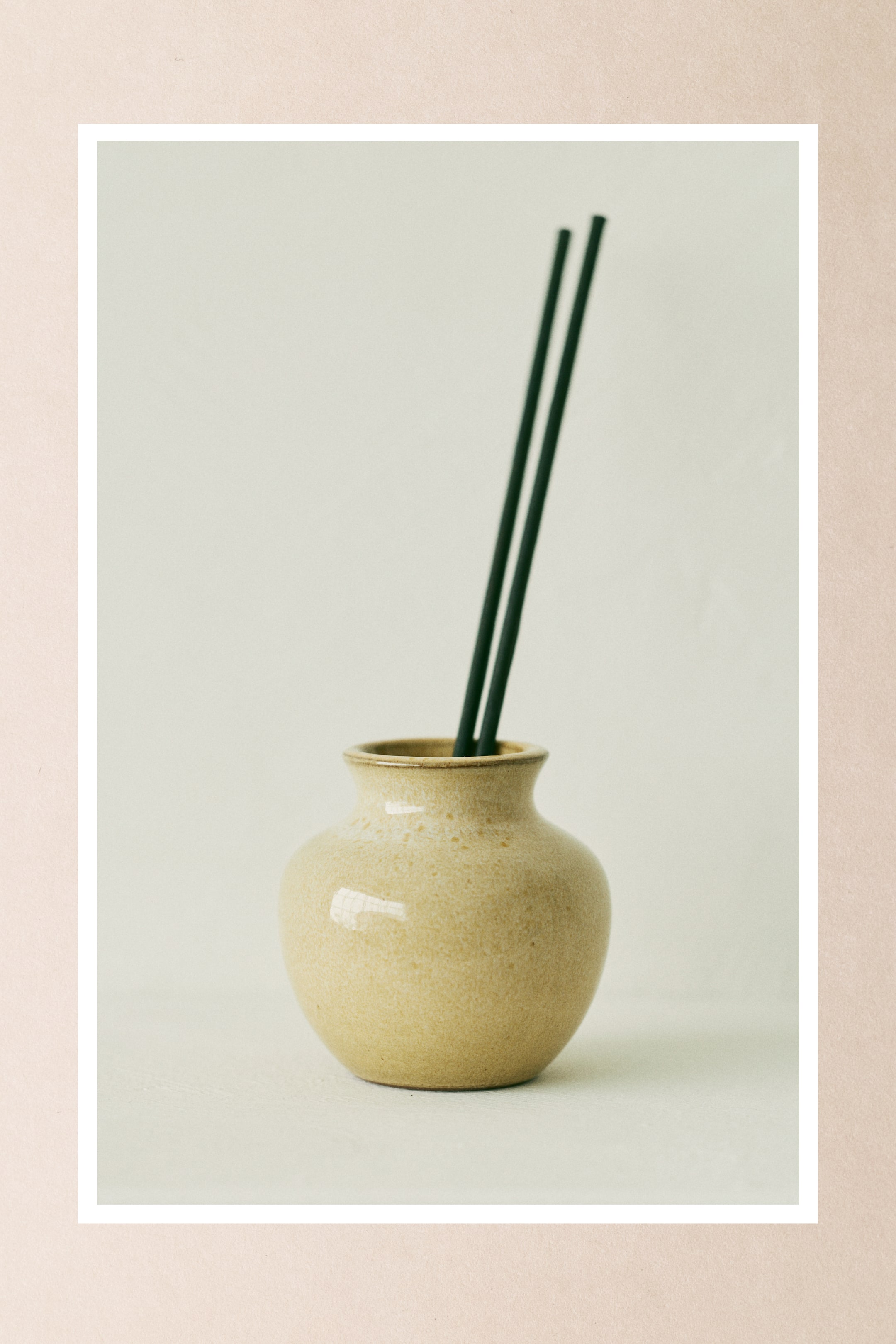 Visa större bild: Två mörka, tunna doftande papperstrån står upprätt och vinklade i en fläckig ljusbrun keramisk vas.
