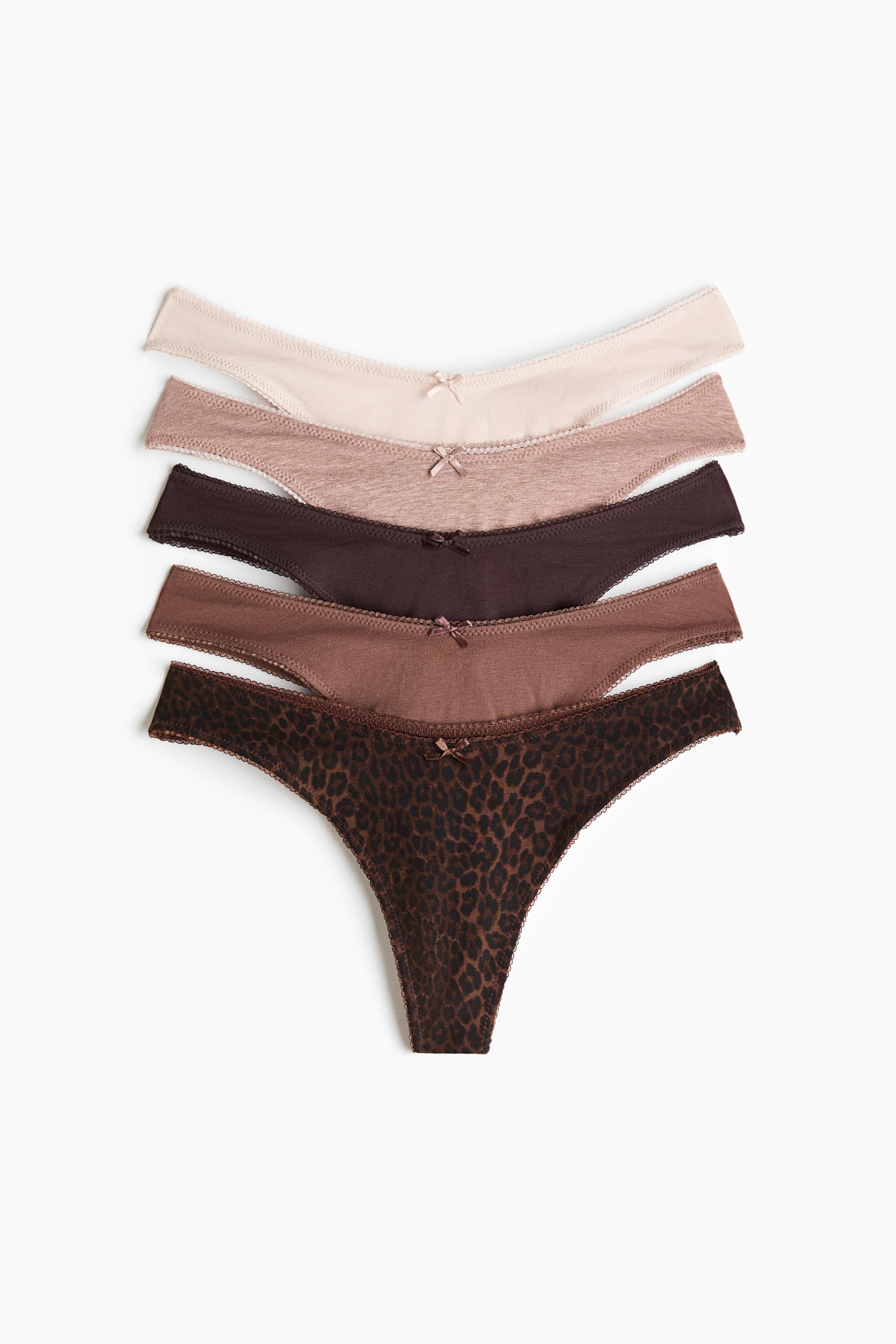 View larger image: Five thong briefs are stacked, showcasing low, V-shaped waistbands. Each brief features a small bow at the center front and delicate trim along the edges, available in varying shades of brown, including light beige, medium brown, dark brown, and a dark brown leopard print.