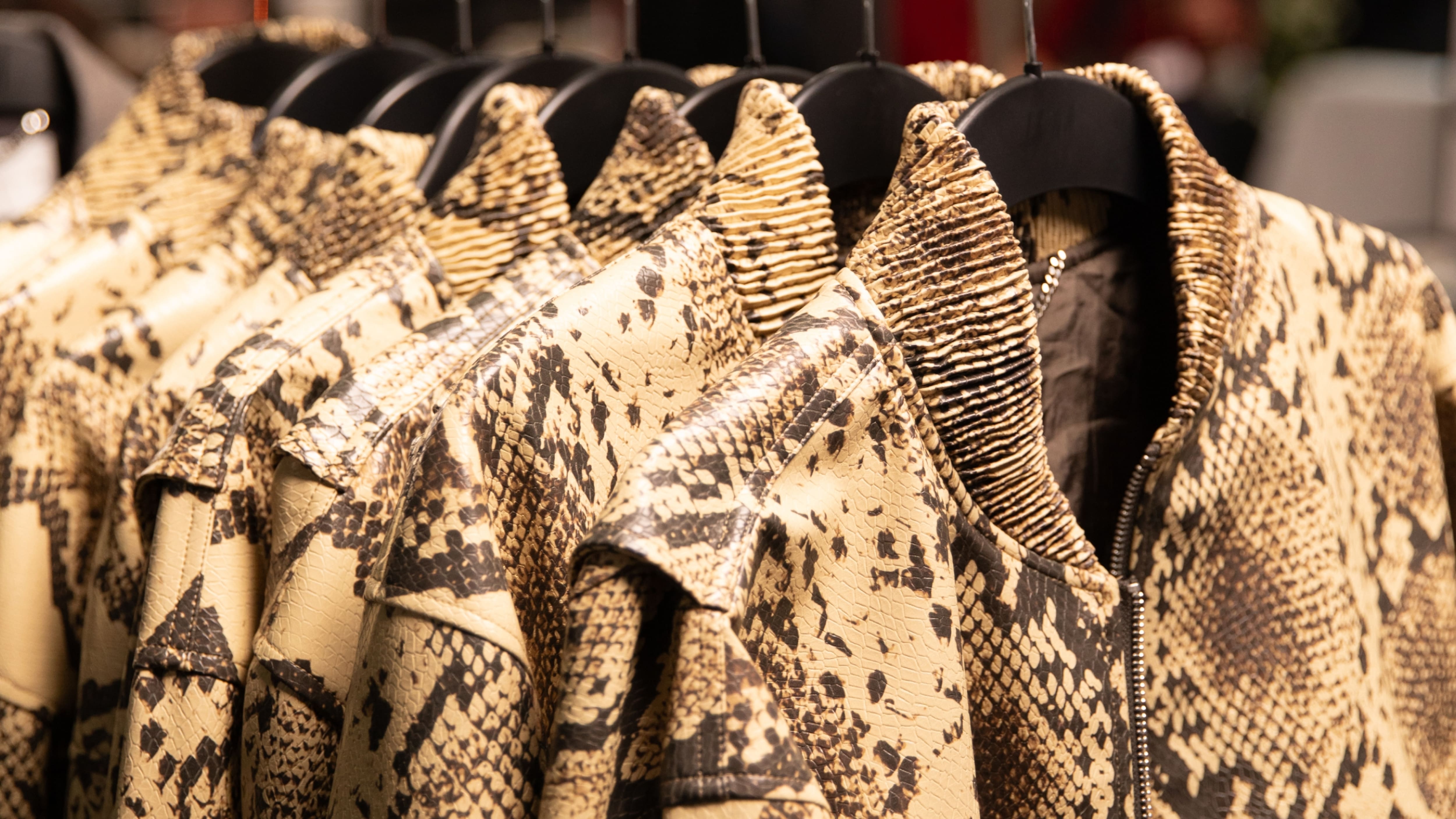 Bomber jackets in snakeskin-effect texture hanging on a rail, crafted from material partly made from recycled vegetable oil and agricultural crop, from the Stella McCartney x H&M 2026 collection.
